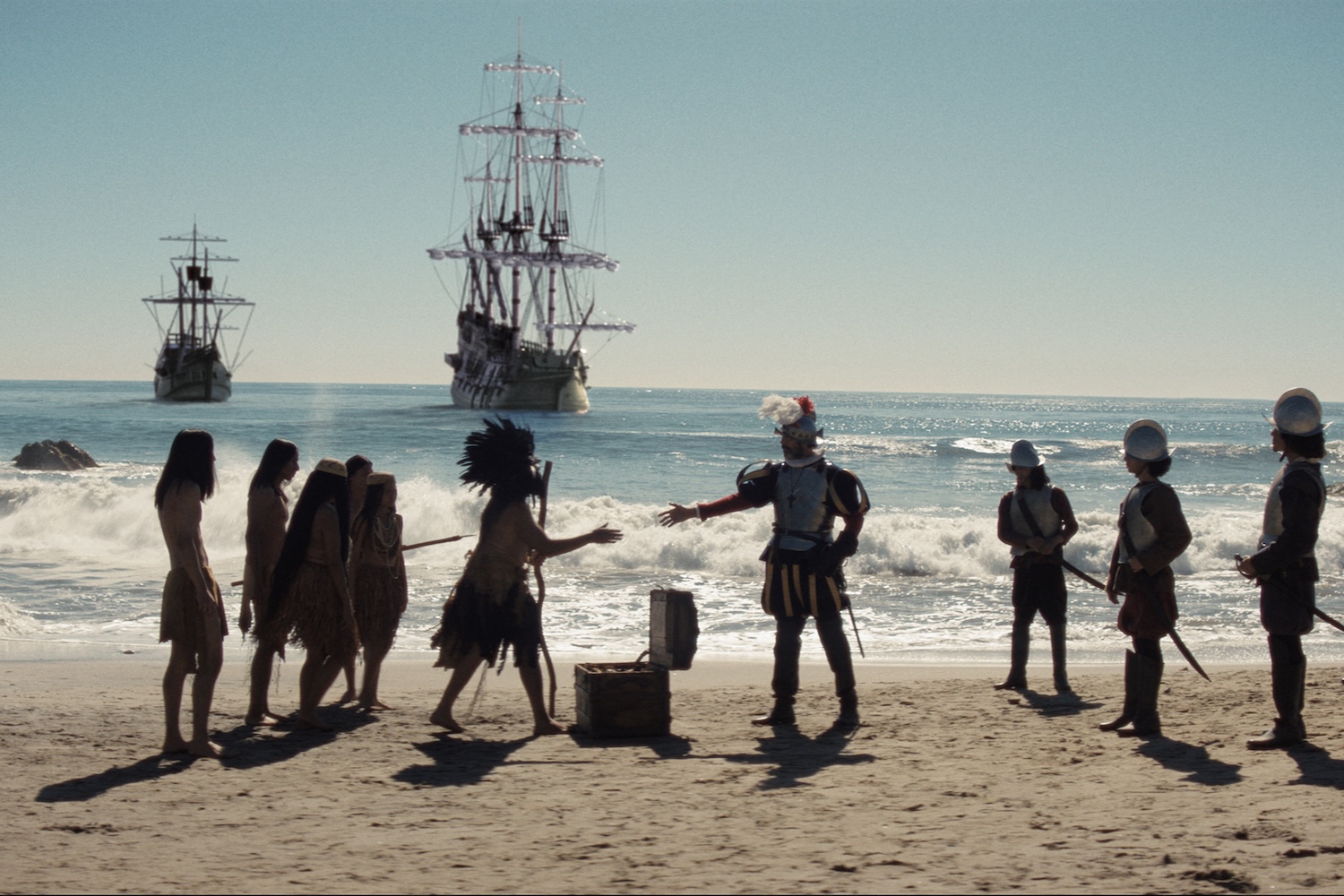 Reenactment of Kumeyaay people standing on a San Diego beach with Spanish ships from the Cabrillo expedition visible in the ocean behind them in 1542.