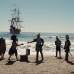 Reenactment of Kumeyaay people standing on a San Diego beach with Spanish ships from the Cabrillo expedition visible in the ocean behind them in 1542.